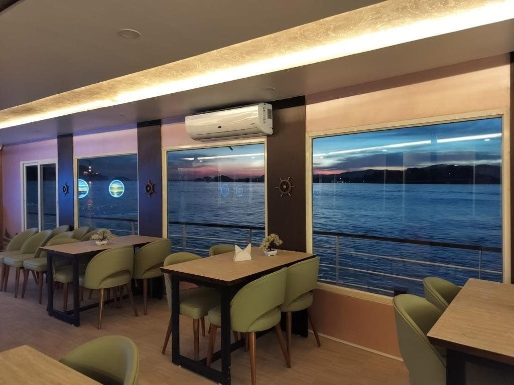 Star Cruise's dining saloon at dusk, the river and far bank visible through full-height windows along the starboard side.